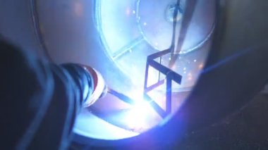 Metal fabrikasında kaynak yapan işçilerin eli. Kaynak kolu iki çelik detay arasında eklem yapıyor. Metal parçalarını kaynaştıran bir usta. Yavaşça kapat..