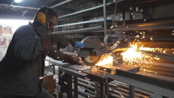 人は金属を切るために切断機を見た 円形のガレージで鋼を見たと認識できない男 安全保護研削金属の産業専門家の労働者 ホットメタルから火花が飛ぶ — ストック動画