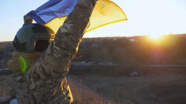 Ukrayna ordusunun kadın askerinin Dolly çekimi. Gün batımında mavi-sarı pankartın üzerinde yükselen. Kamuflaj üniformalı genç kız Ukrayna bayrağını taşraya çekti. İstila direnişi kavramı.