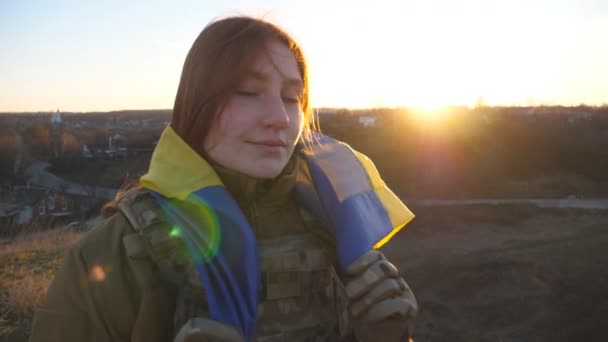 笑顔の女性ウクライナ軍兵士の肖像画は カメラを見て ウクライナのフラグを保持しています 軍の制服を着た幸せな少女の光景は 黄色の青い旗で立っている ロシアの侵略に対する勝利 — ストック動画