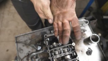 Atölyedeki genç tamircinin kirli elleri. Tamirci garajda sıkı çalıştıktan sonra kirli kollarını yakıt yağından temizliyor. Bakım hizmeti kavramı. Yavaş çekim.