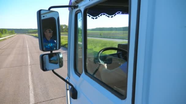 移動車のサイドミラーに反映サングラスでトラック 男田舎道を通って目的地に乗馬を運転 貨物輸送の概念 美しい背景 スローモ閉じます — ストック動画
