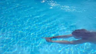 Saydam berrak suyla havuzda yüzen tanınmayan bir kadın. Genç kız yaz tatilinde otel havzasında yüzüyor. Yaz tatili kavramı. Yavaş çekim kenar görünümü