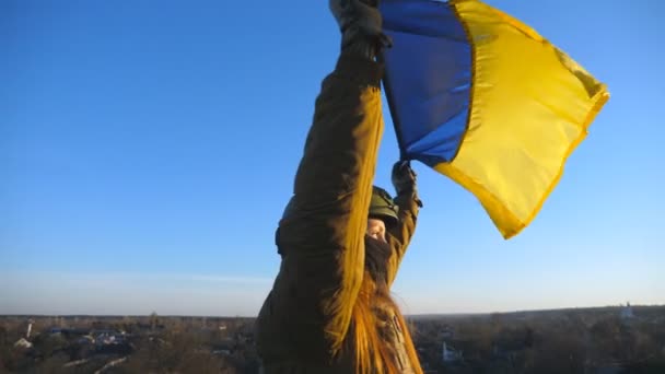 우크라이나 장교가 우크라이나 국기를 흔들고 군복을 헬멧을 언덕에서 깃발을 들었다 — 비디오