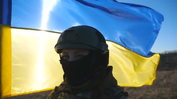 Militäranwärterin Der Ukrainischen Armee Blickt Vor Schwenkender Blau Gelber Fahne — Stockvideo