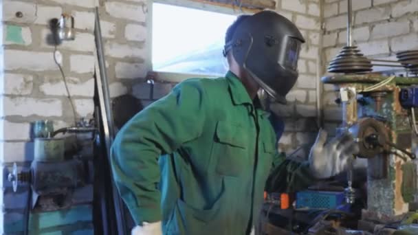 快乐的男焊工戴着防护面罩在车间里跳舞 穿着制服的快乐的修理工 享受着车库的乐趣 无法辨认的机械师高兴地完成了工作 慢动作 — 图库视频影像