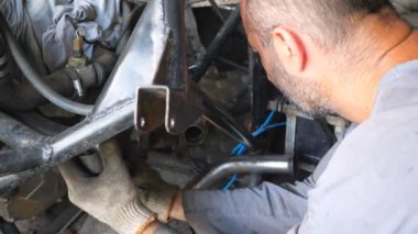 Tanımlanamayan tamirci tamir aracı. Erkek tamirci otomobili tamir ediyor. Otomobil ustası işini garajda ya da atölyede yapıyor. Adam otomatik servise başladı. Yavaş çekim. Yakın çekim..