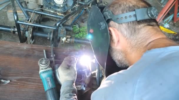 无法辨认的焊机在车库里或车间焊接金属零件 机械师使用焊机为他的工作和保护面罩从闪光 慢动作关闭 — 图库视频影像