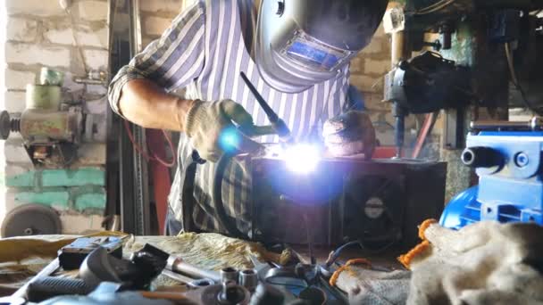 修理者焊接汽车的一些细节 在车库里或车间与焊机和其他专业设备一起工作的机械师 焊机使用保护膜从闪光 慢动作多利射门 — 图库视频影像