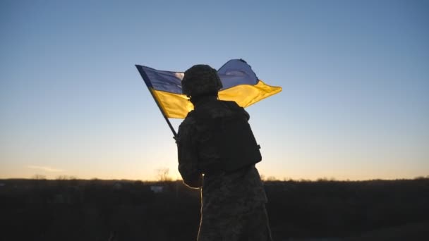 Украинский Военный Стоит Вершине Холма Размахивая Сине Желтым Знаменем Против — стоковое видео