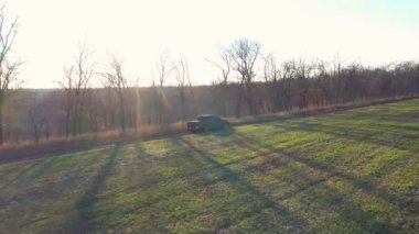 Saha yakınındaki yolda giden siyah arabanın hava görüntüsü. Otlağın yakınındaki kırsal yolda giden off-road aracı. Kamyonet kırsala doğru gidiyor. Arka planda güzel güneş ışığı.