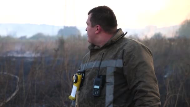 Άντρας Κουρασμένος Πυροσβέστης Στέκεται Στο Παρασκήνιο Της Καύσης Ξηρό Γρασίδι — Αρχείο Βίντεο