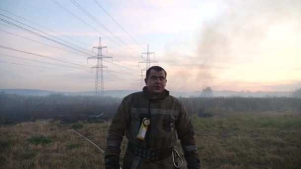 Άντρας Κουρασμένος Πυροσβέστης Στέκεται Στο Παρασκήνιο Στο Καπνιστό Γκαζόν Στην — Αρχείο Βίντεο