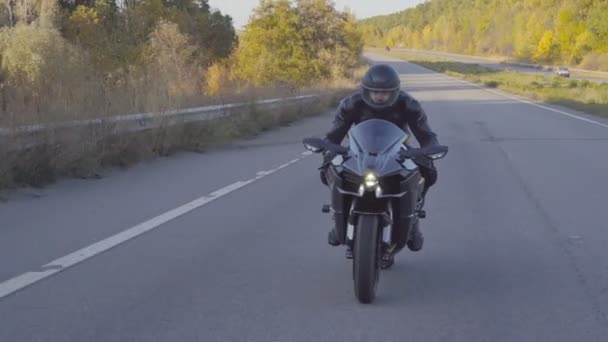 헬멧을 도로에서 빠르게 달리는 자전거를 자전거의 오토바이 운전자는 초가을에 도로에서 — 비디오
