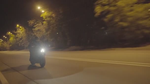 男性バイカーは夜の街で彼の現代的なバイクに乗って移動します 夜間道路で明るいヘッドライトを持つ強力なスポーツバイクに乗ってオートバイ主義者 旅行中に若い男が自転車を運転する 閉じろ — ストック動画