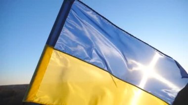 Güneş ışığının arka planında rüzgarda dalgalanan Ukrayna bayrağı. Kırsalda çırpınan Ukrayna 'nın mavi-sarı sembolü. Rus saldırısına karşı barış ve destek kavramı. İstila direnişi.