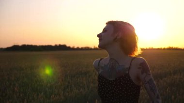 Kısa siyah elbiseli neşeli punk kızı buğday çayırlarında dolaşırken aylaklık ediyor. Dövmeli mutlu bayan hippi gün batımında yeşil arpa tarlasından geçiyor. Özgürlük kavramı.
