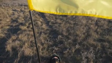 Ukrayna bayrağıyla Ukrayna ordusunun kadın askeri doktoru çayırdaki kuru çimlerin üzerinde yatıyor. Kamuflaj üniformalı, güneşli bir günde ulusal pankartıyla sahada dinlenen genç bir kız. Savaşta zafer. Dolly vurdu..