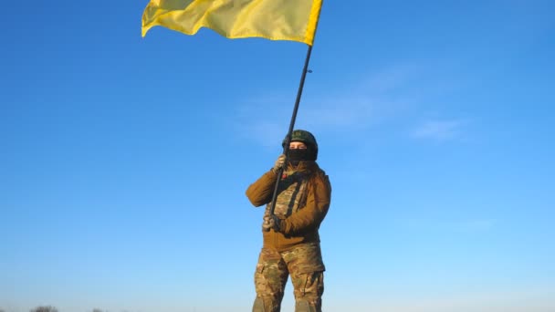 ウクライナの旗を振っている女性ウクライナ軍兵士 軍の制服を着た女性とヘルメットは青い空に対して旗を持ち上げた ロシアの侵略に対する勝利 侵入抵抗概念 — ストック動画