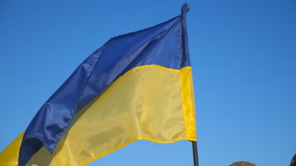 青い空に対してカメラにポーズウクライナのフラグを持つウクライナ軍の軍のカップル 田舎の青黄色のバナーとカモフラージュ制服の若い兵士の肖像画 侵入抵抗 — ストック動画