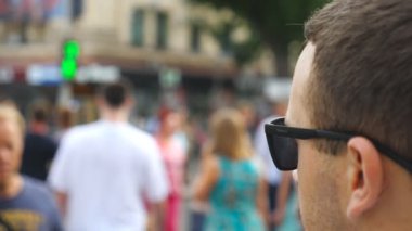 Güneş gözlüklü genç iş adamının şehir merkezinde karşıdan karşıya geçerken çekilen fotoğrafı. Büyük şehirde yaya geçidinde yürüyen kendinden emin bir erkek girişimci. İşe gidip gelen yakışıklı bir yönetici. Yavaş çekim. Yakın çekim..