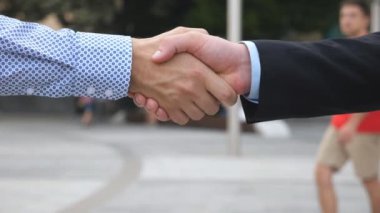 İki genç kendine güvenen iş adamı bulanık şehir geçmişiyle el sıkışıyor. Erkek meslektaşlar şehir ortamında birbirlerini selamlarlar. İş ortaklarının el sıkışması. Ağır çekim. Yakın çekim..