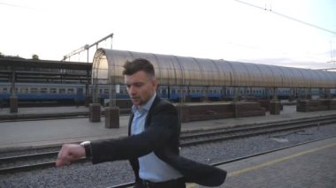Başarılı bir işadamı tren istasyonunda koşuyor ve saate bakıyor. Genç adam trene geç kaldı. Demiryolu yakınında koşan bir iş adamı. İş gezisi kavramı. Yavaş çekim. Yakın çekim..