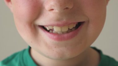 Gülümseyen genç çocuk yakın çekim. Yüzündeki mutlu ifadeyi ile yakışıklı çocuk portresi. Ayrıntı görünümü mutlu çocuk yüzünde. Ağır çekim.