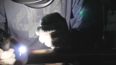 Kaynakçı Kaynak işi profesyonel ekipman ve garaj veya atölye koruyucu maske kullanarak kapatın. Adam metal parçalar kaynak. İş kapalı kaynak yanıp söner. Ağır çekim.