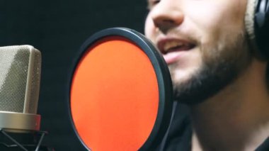 Unrecognizable male singer in headphones singing song at sound studio. Young man emotionally recording new melody or song. Working of creative musician. Show business concept. Slow motion.