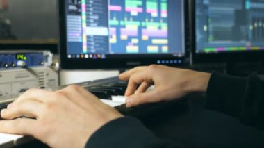Ses kayıt stüdyosundaki synthesizer 'da çalan erkek müzisyenin elleri. Mens arms solo müzik ya da yeni melodi çalıyor. Piyanistin parmaklarını piyano tuşlarına yakın tut. Yavaş çekim.
