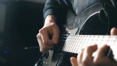 Dizeleri, gitarist parmakları kapatın. Mens çalış solo rock müzik silah. Eller erkek müzisyen elektro gitar çalmak. Stüdyoda güzel siyah arka plan. Ağır çekim yakın çekim.