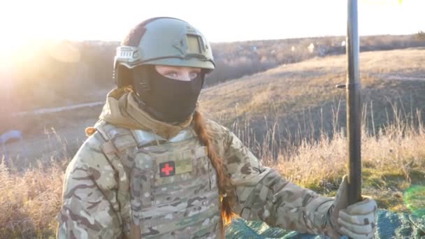 乌克兰军队的女军医们坐在战场上升起国旗 身着迷彩服的年轻女子举着一面飘扬的乌克兰国旗 以抵御日落 战胜俄罗斯侵略的胜利 — 图库视频影像