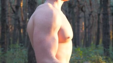 Çıplak gövdeli kaslı bir adam ağır ağırlık kaldırıyor. Ormanda çalışan güçlü bir adam. Sporcu kütük kullanarak dışarıda egzersiz yapıyor. Spor anlayışı ve aktif yaşam tarzı. Yan Görünüm Kapat.