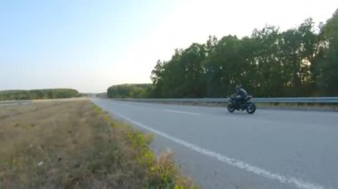 Otoyolda motorsiklet süren kasklı motosikletliyi takip edin. Adam sonbahar kır yolunda motosikletiyle yarışıyor. Yolculuk sırasında bisiklet süren adam. Özgürlük ve macera kavramı. Hava görüntüsü.