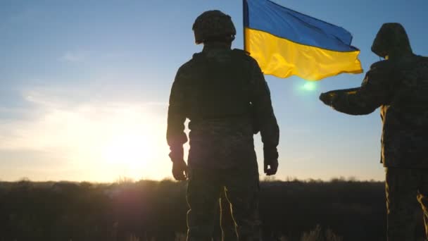 乌克兰军队的士兵站在山顶上升起乌克兰国旗 身穿军服的人拿着飘扬的旗帜作为战胜俄国侵略的胜利的象征 欧洲战争的结束 — 图库视频影像
