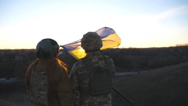 乌克兰军队的士兵在日落的背景下升起乌克兰国旗 身穿军服的人升起了黄蓝色的旗帜 战胜俄国侵略的胜利抵抗入侵的概念 — 图库视频影像