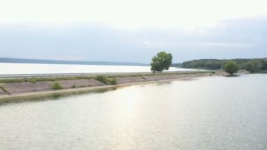 Motosikletlinin göl kenarındaki yolda motosikletiyle yarışırken çekilmiş bir fotoğrafı. Adam yaz günü baraj yolunda bisiklet sürüyor. Modern spor motosikletle nehir köprüsünün üzerinden uçuyor. Üst görünüm.