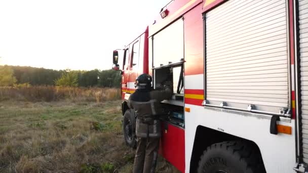Fiatal Tűzoltó Egyenruhában Kihozza Felszerelést Piros Furgonból Profi Tűzoltó Készül — Stock videók