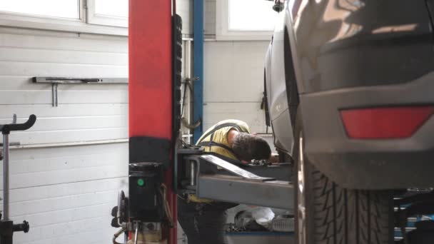 维修工身穿制服 在车间或车库里修理汽车故障 在汽车服务部门与起重车辆一起工作的专业技师 定期汽车维修的概念 慢动作 — 图库视频影像