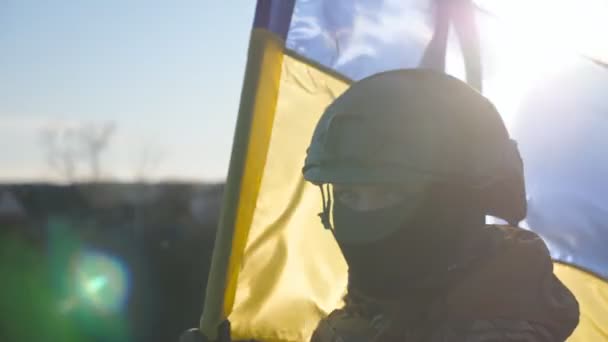 イギリス軍の女性兵士が青い黄色の旗を振ってカメラを覗き込む 軍用ヘルメットとバラカバラの少女の肖像画は 晴れた日に国旗を掲げています ロシアによるウクライナ侵攻 — ストック動画