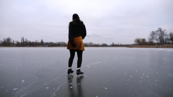 女滑雪者在冰面上滑冰 女运动员在冰封的河流或湖中进行花样滑冰训练 妇女提高技能 在寒冷的冬季有积极的闲暇时间 慢动作 — 图库视频影像