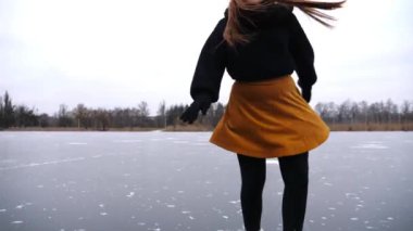 Donmuş nehirde kadın patenci eğitim rotasyonu becerileri. Buz pateni pistinde kayan artistik paten giyen genç bir kız. Sporcu kadın soğuk havada gölde paten kayıyor. Dondurucu kış gününde aktif eğlence.