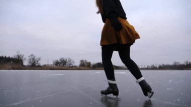 Genç sporcu kadın dışarıda idman yaparken buz pateni sahasına düşüyor. Buz nehrinde buz pateni antrenmanı yapan kadın patenci. Dondurucu kış gününde aktif eğlence. Sağlıklı yaşam tarzı kavramı