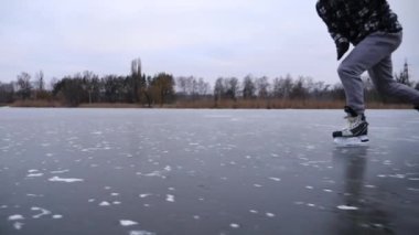 Artistik patenci genç adam antrenman sırasında buzda hızlı kayıyor. Adam donmuş nehirde kayıyor. Erkek hokey oyuncusu soğuk kış gününde gölde becerilerini geliştiriyor. Kış zamanı aktif bir eğlence. Yavaş çekim.