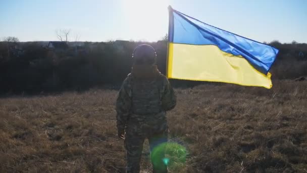 阳光灿烂的日子里 女兵多莉举着一面飘扬的国旗 身穿军服的妇女站在战场上升起乌克兰国旗 战胜俄罗斯侵略的胜利 — 图库视频影像