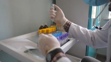 Bilim adamı COVID-19 için tedavi geliştiriyor. Tıbbi maske takan doktor ve eldivenler şırınga kullanarak test tüplerini sıvıyla dolduruyor. Laboratuvarda çalışan bir doktor. Sağlık ve koronavirüs salgını kavramı.