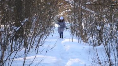 Kış ormanlarında yürüyen güzel bir kadın. Soğuk ve soğuk havada karlı ormanda gezinen genç bir kız. Tasasız kadın dışarıda dinleniyor. Kış konsepti Yavaş çekim.
