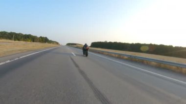 Sonbahar otobanında motosiklet süren motosikletliyi takip edin. Motosikletli, kır yolunda motosikletiyle yarışıyor. Yolculuk sırasında bisiklete binen adam. Özgürlük ve macera kavramı. Hava görüntüsü.