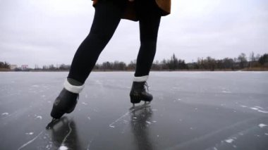 Doğada buz pateni pistinde kayan artistik patenli kadın bacakları. Donmuş nehirde kadın patenci eğitimi. Gölde genç kız eğitim becerileri. Kış zamanı aktif bir eğlence. Yavaş çekim.